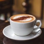 A perfectly brewed Spanish latte served in a ceramic cup, topped with latte art, accompanied by sugar and cinnamon sticks.